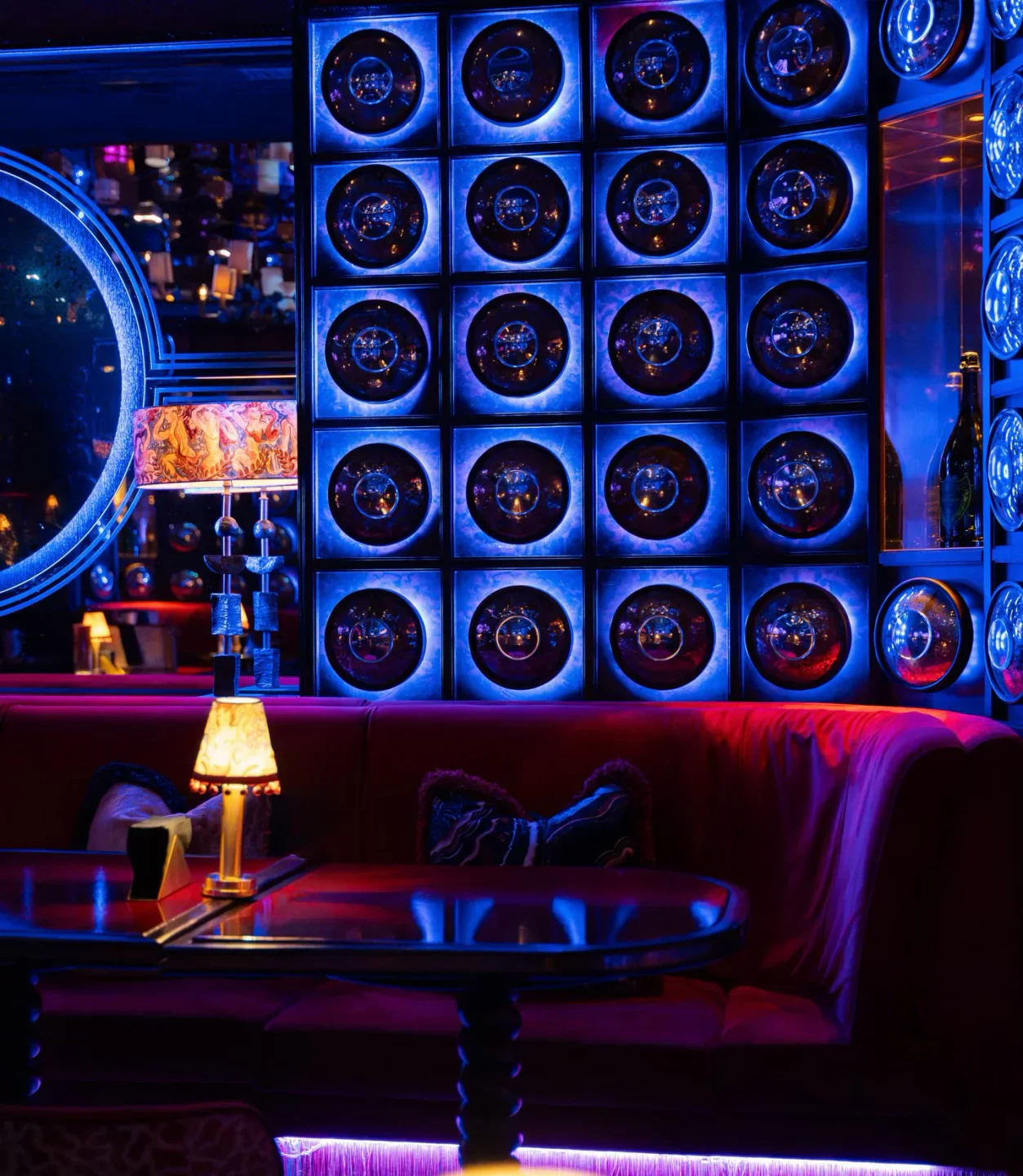 Luxurious red velvet booths and vibrant blue neon lighting inside NYX nightclub in Marbella.