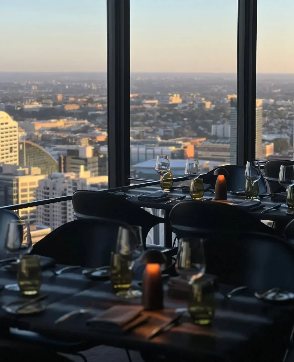 Dining tables at O Bar & Dining in Sydney with stunning city views at sunset.