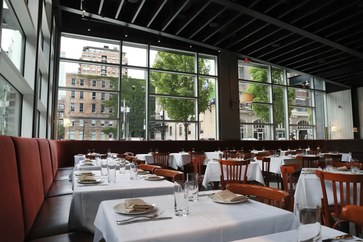 Interior of Obélix restaurant in Chicago, with tables set by a large window.