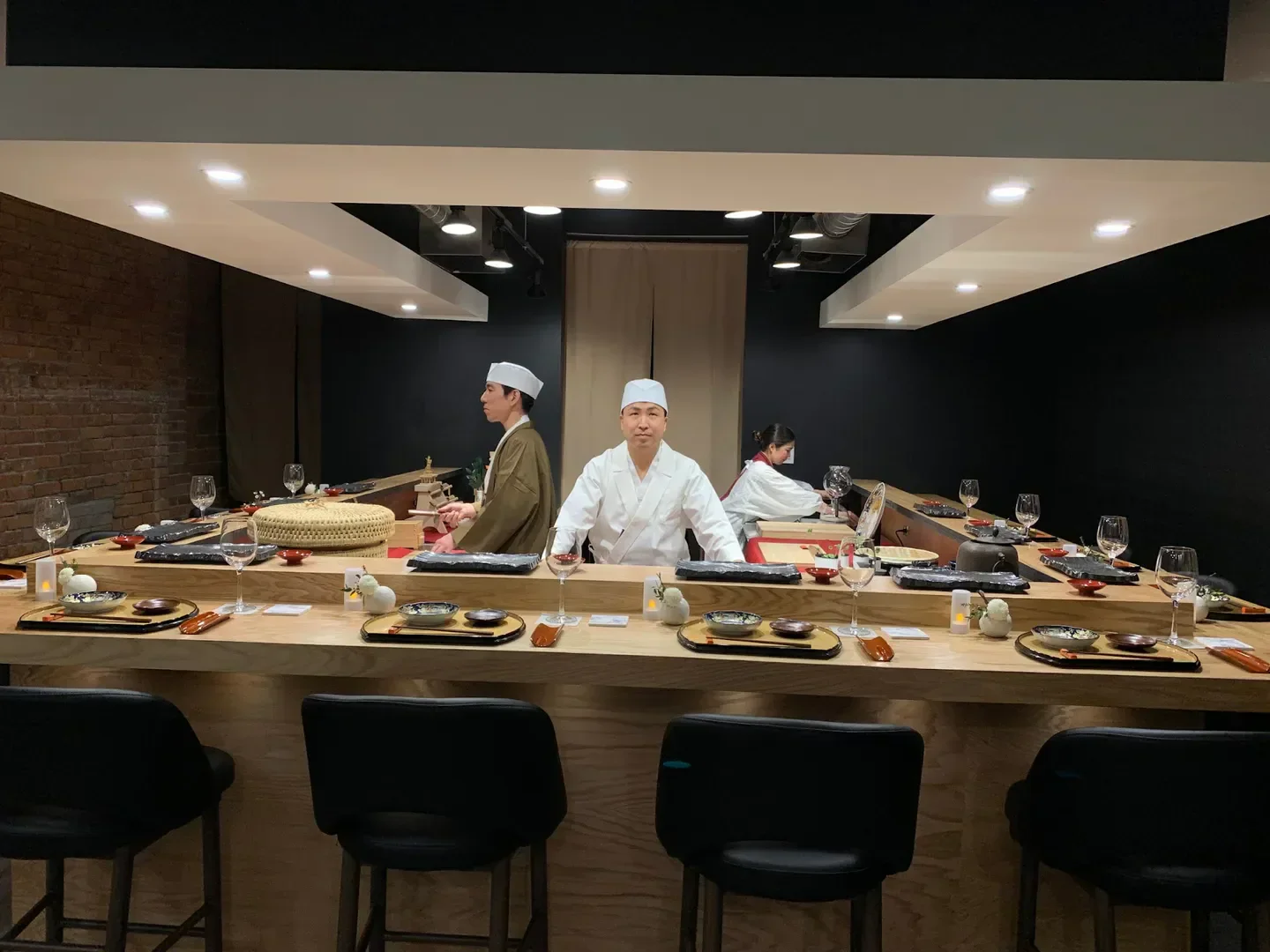 Chefs preparing food at Okeya Kyujiro - Montréal, a restaurant in Montreal, with elegant table setting.