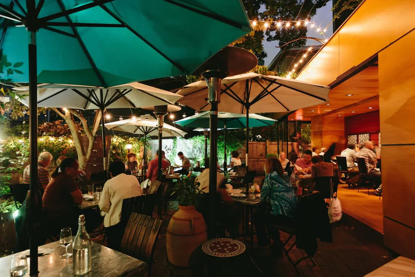 Outdoor dining at Oleana restaurant in Boston, with patio umbrellas and string lights.