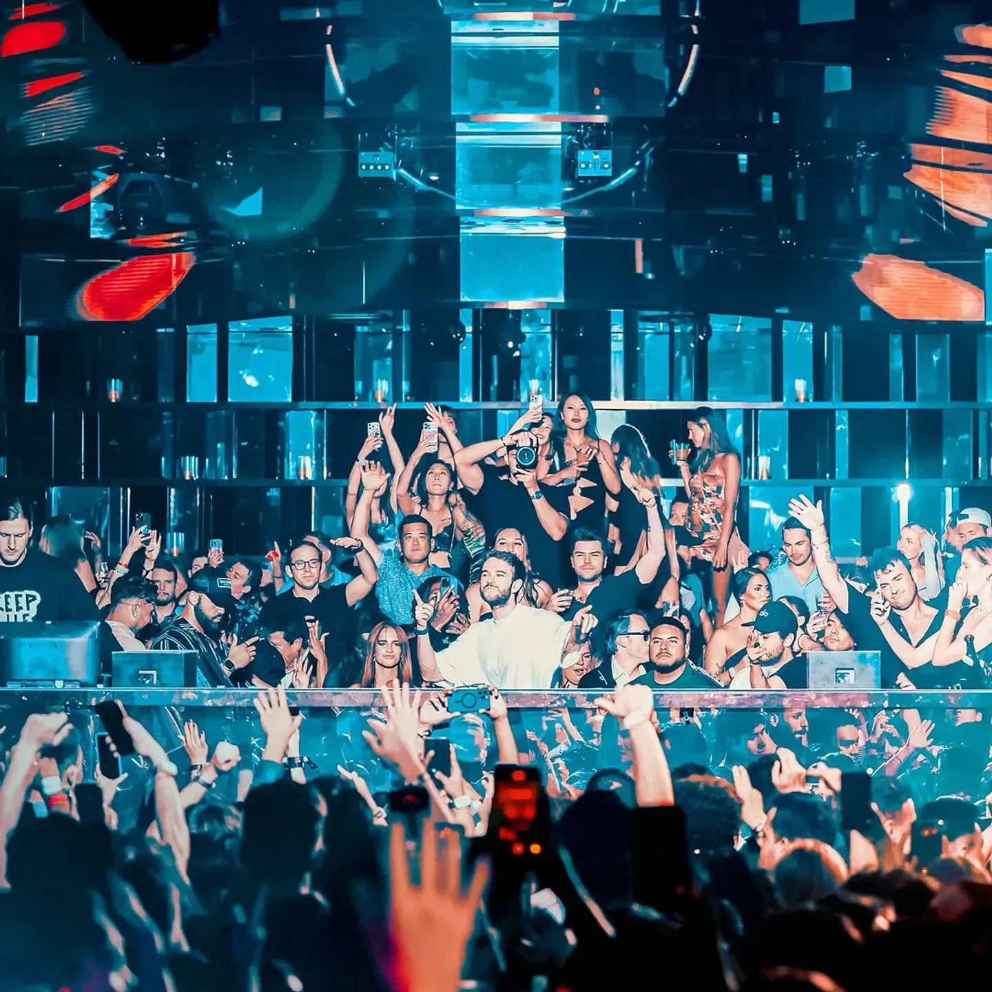 Energetic crowd at Omnia nightclub in Las Vegas with raised hands and vibrant lights.