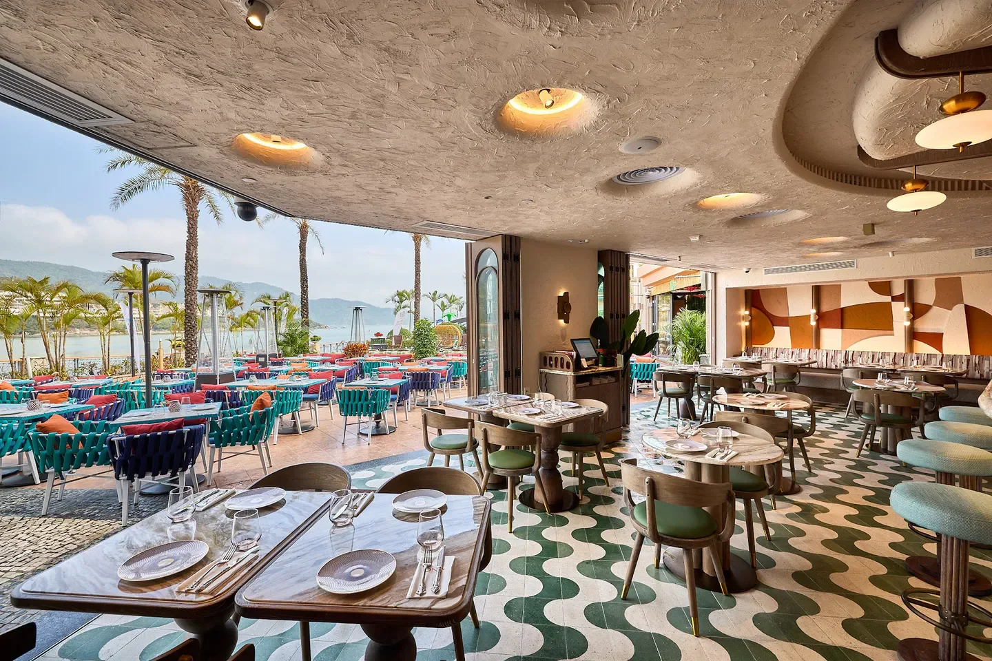 Stylish interior and outdoor seating at ÓNA restaurant in Hong Kong, overlooking the water