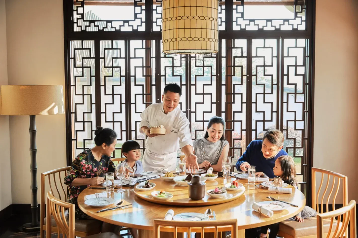 Chef serving a family at One Harbour Road restaurant in Hong Kong