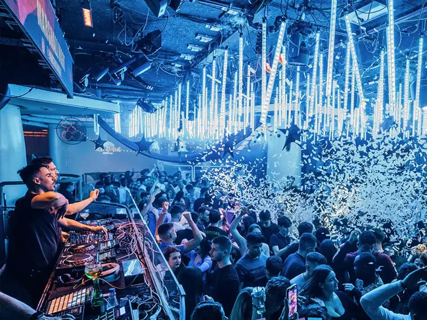 Energetic crowd partying at Pacha Barcelona nightclub with confetti and DJs.