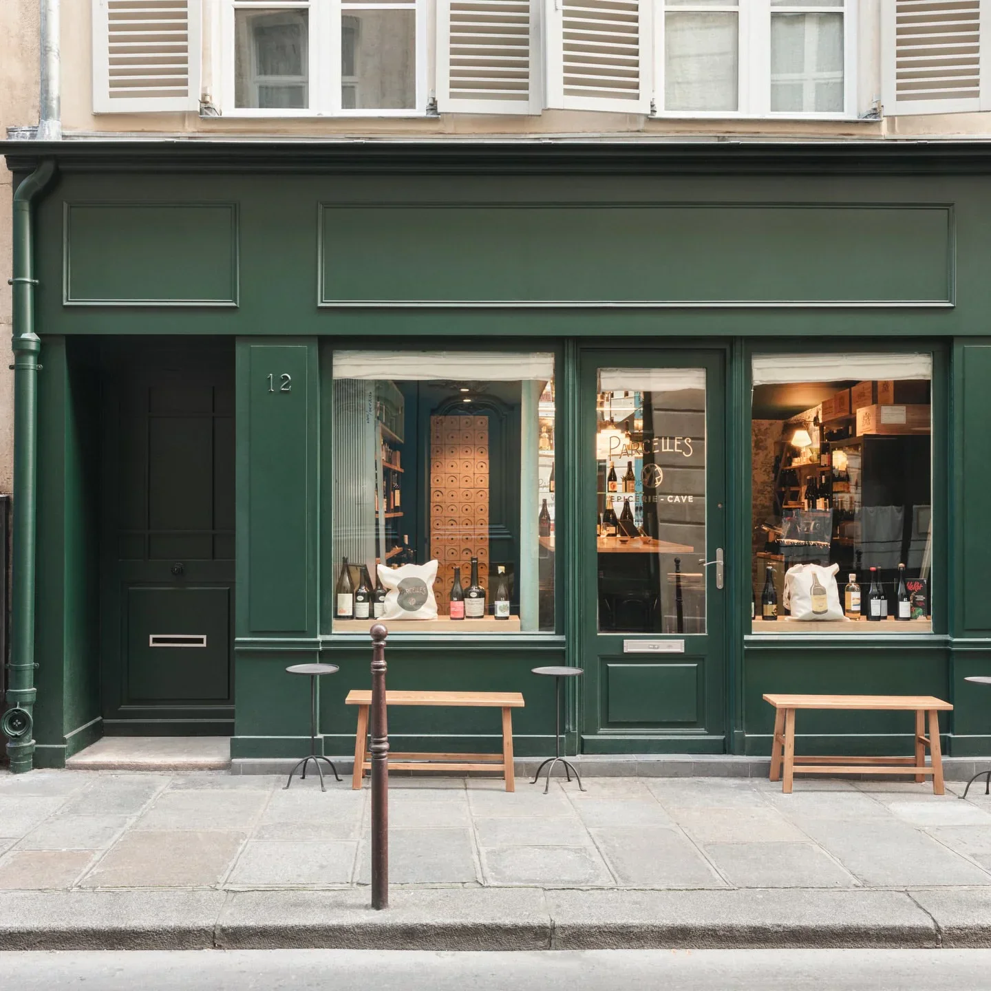 Parcelles restaurant exterior in the city with green facade and window display of wine bottles