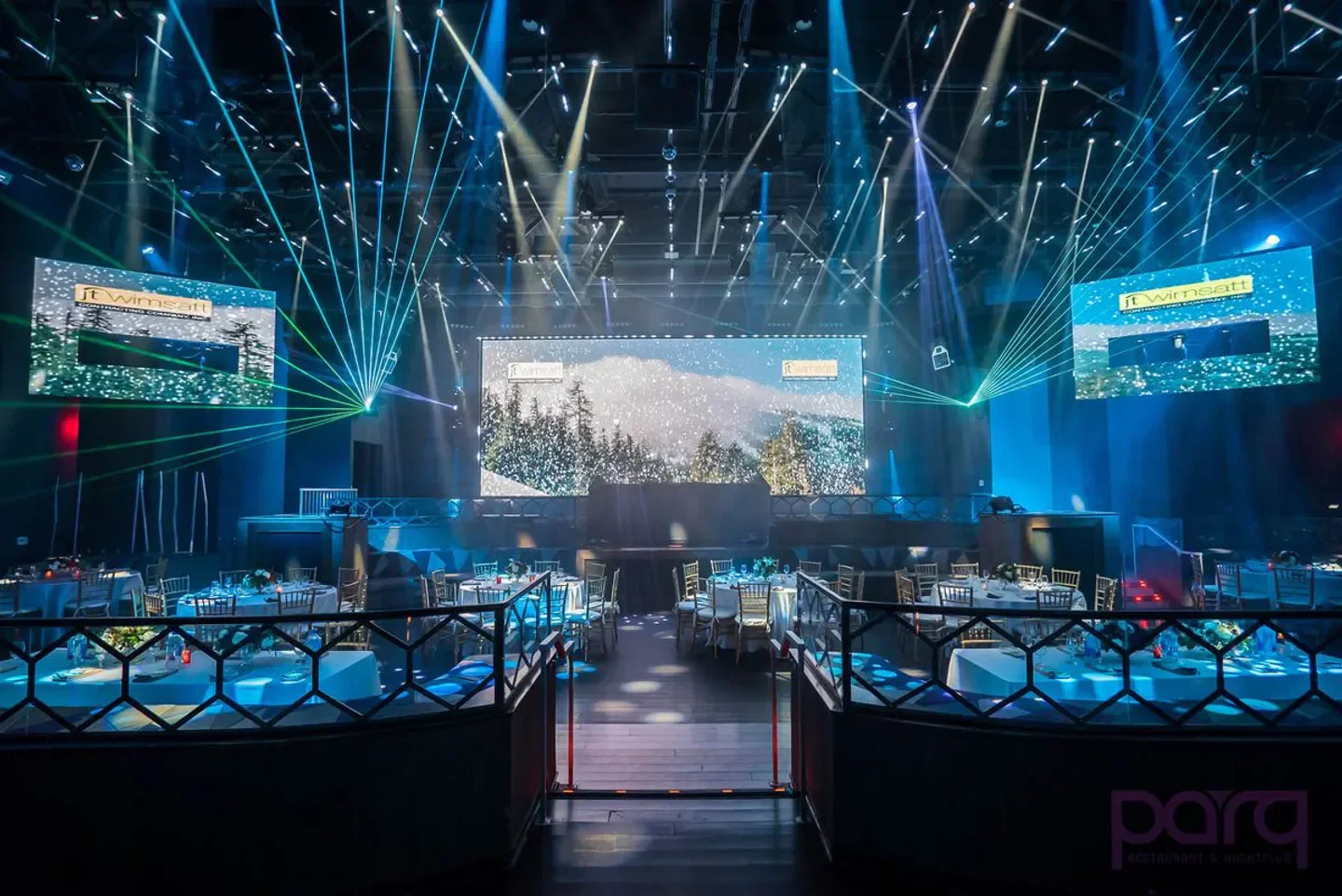 Inside Parq nightclub in San Diego with stage, lights and tables set for dining.