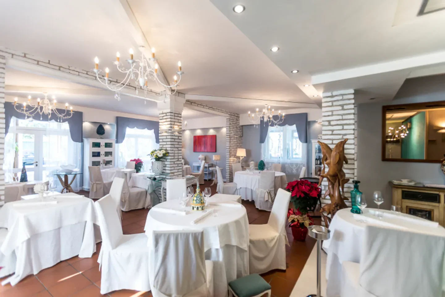 Elegant interior of Pascucci al Porticciolo restaurant in Lazio, featuring white tablecloths and chandeliers.
