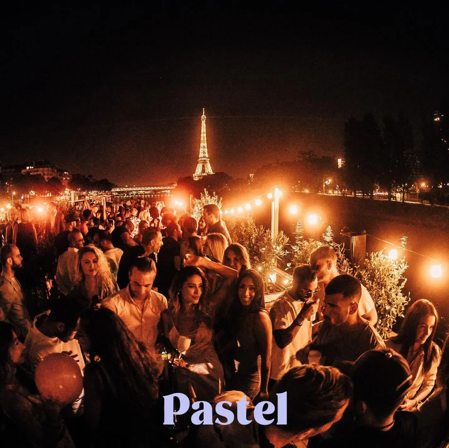 Nightclub Pastel in Paris with Eiffel Tower view, busy crowd and string lights.