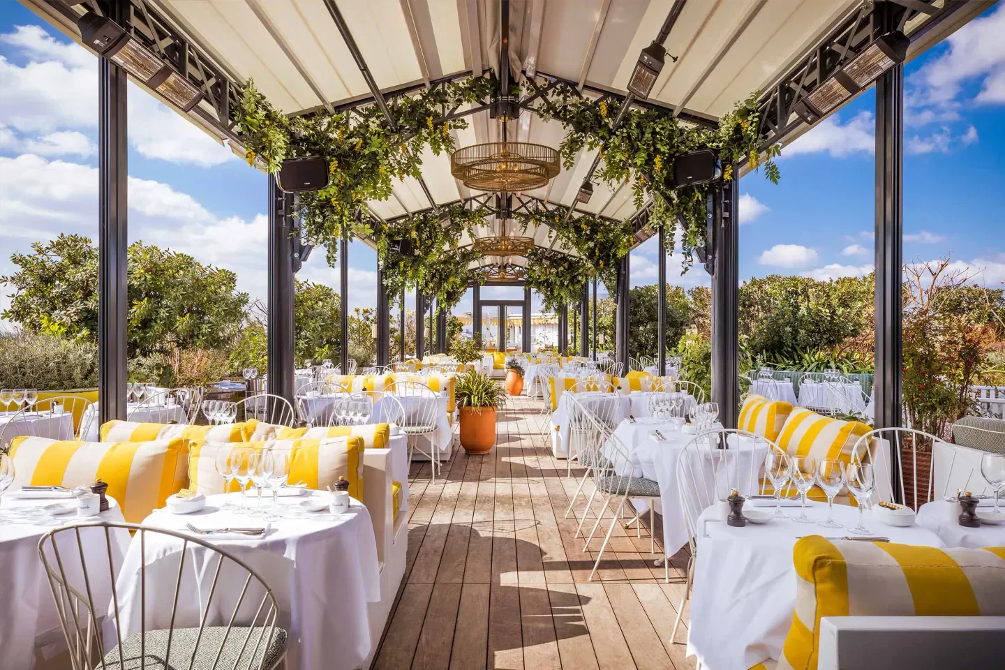 Elegant dining space at Perruche restaurant in Paris, featuring yellow accents and greenery.