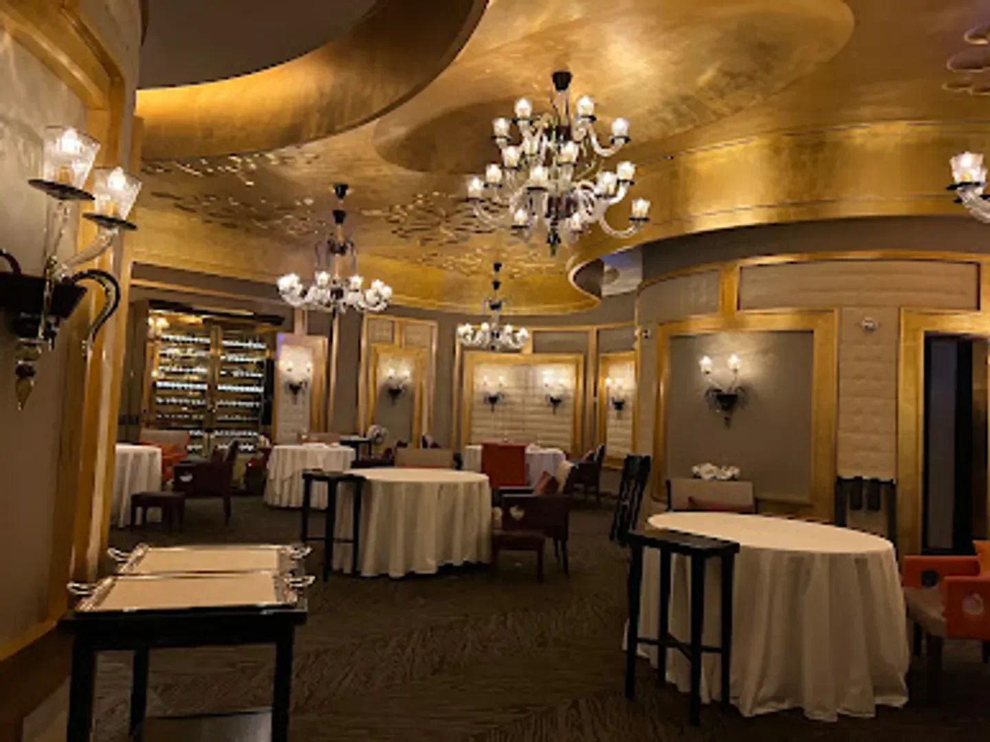 Elegant dining room interior at Pierre Gagnaire in Seoul, with chandeliers and round tables.