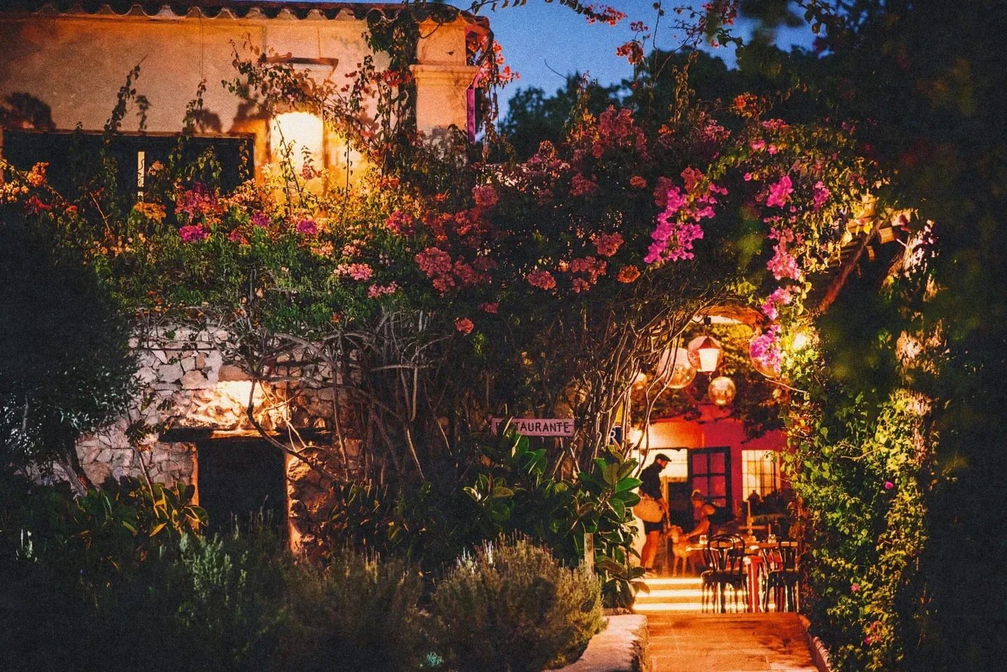 Romantic entrance to Pikes restaurant in Ibiza, adorned with flowers and warm lighting.