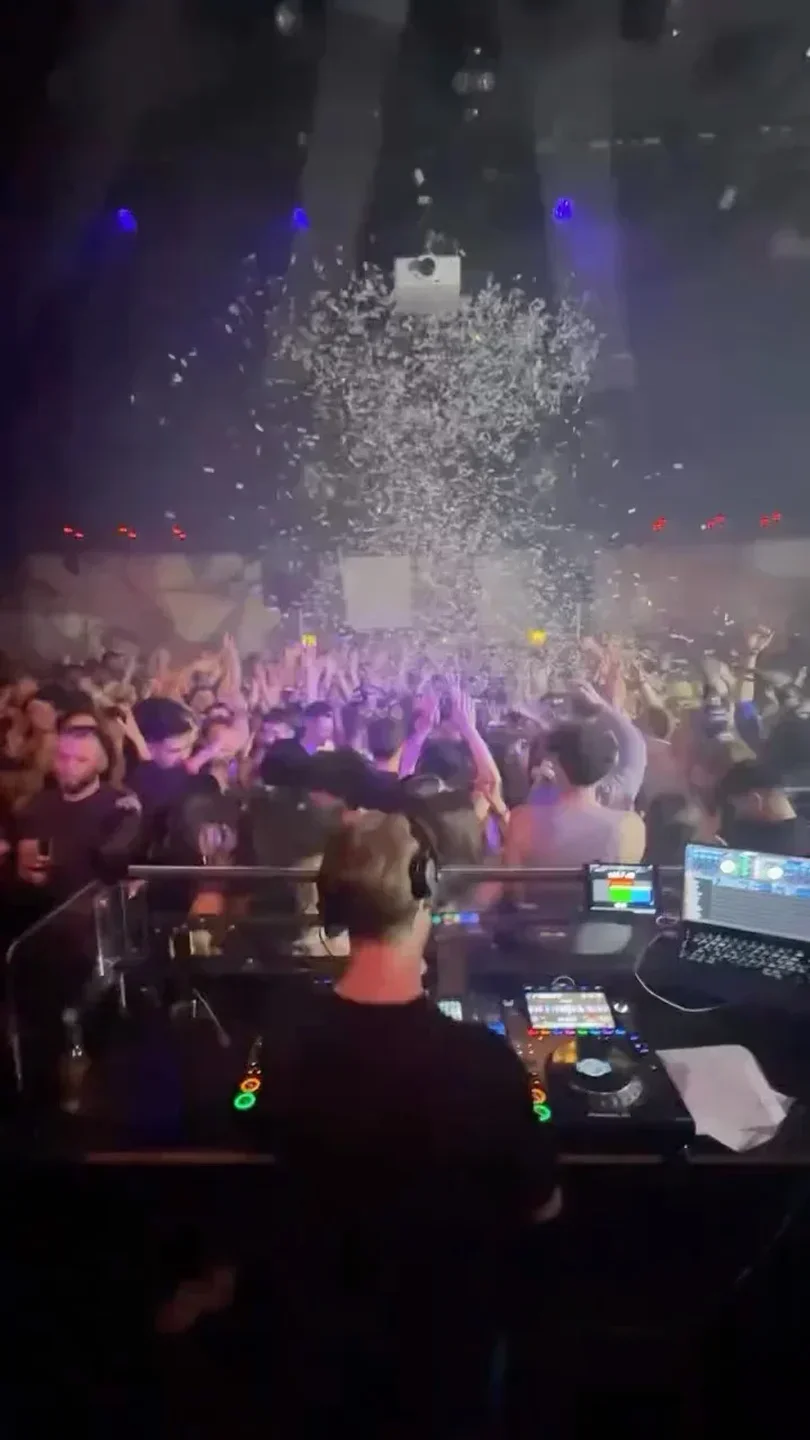 DJ at Plaza Zurich nightclub with crowd, confetti and vibrant lights.
