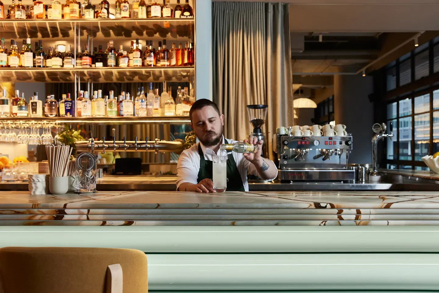 Bartender pouring a drink at Poetica Bar & Grill in Sydney, showcasing stylish bar interior.