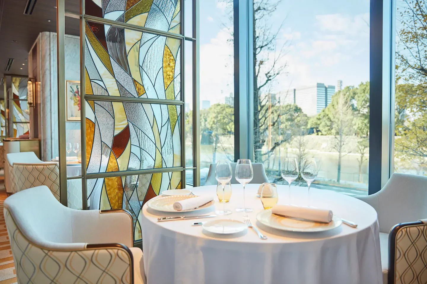 Elegant dining at PRUNIER Tokyo restaurant, featuring a stained glass window with a view