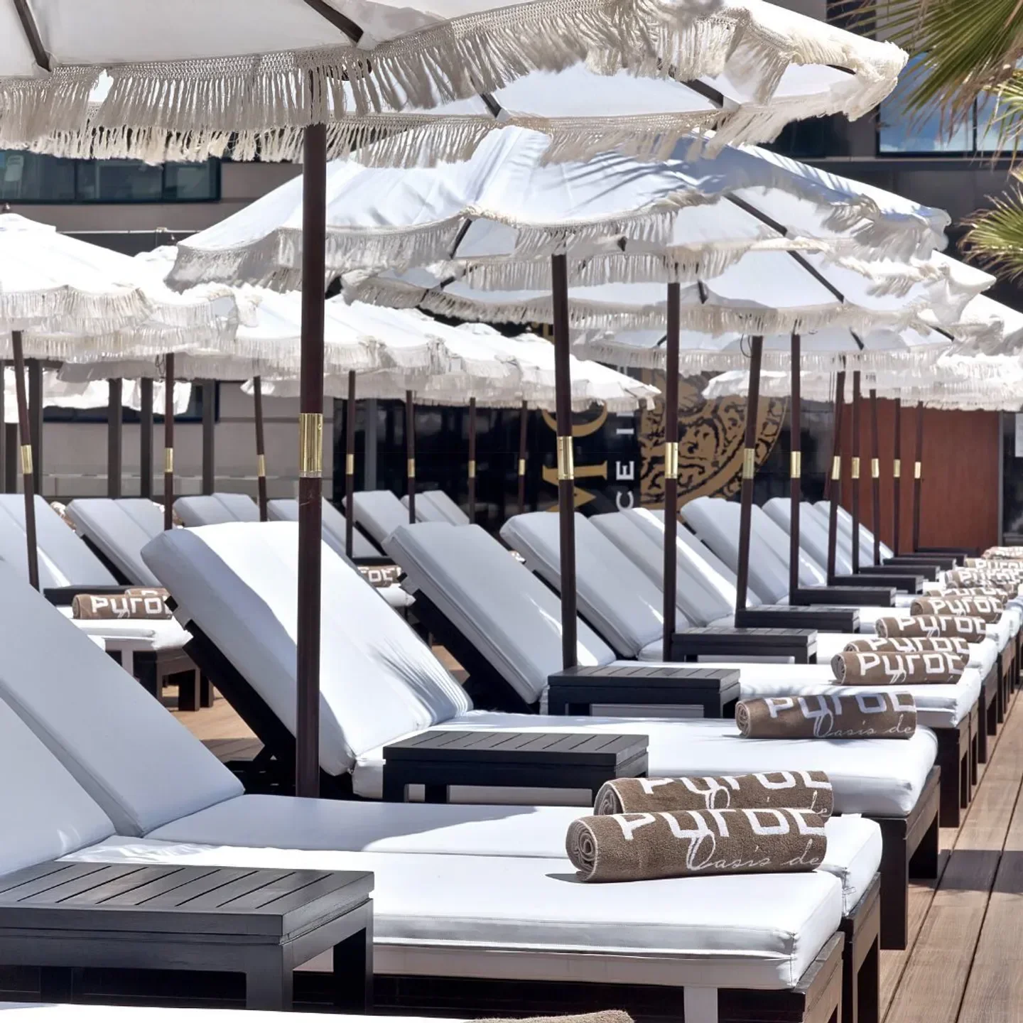 Relaxing lounge chairs and parasols at Puro Beach Barcelona beach club.