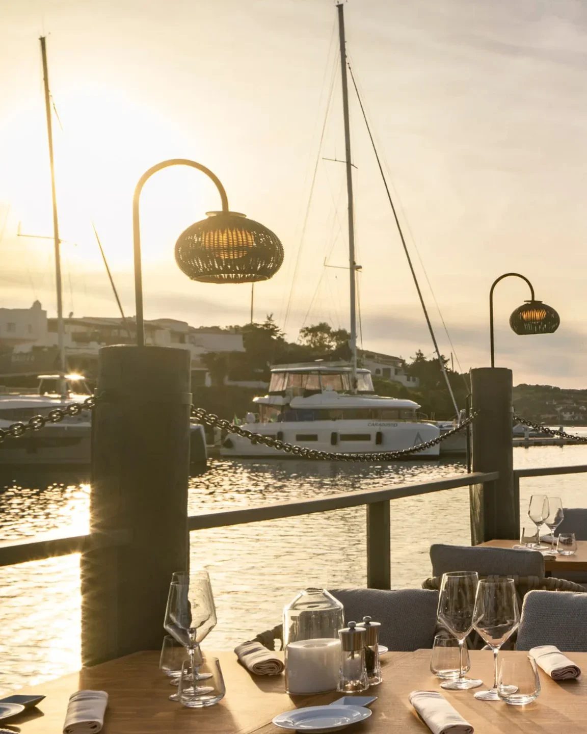 Waterfront dining ambiance at Quattro Passi Al Pescatore in Porto Cervo during golden hour with yachts nearby.
