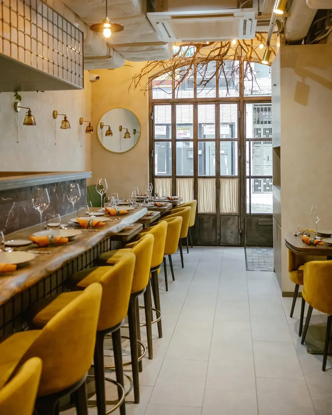 Interior of Racines restaurant in Hong Kong, featuring stylish yellow seating and bar area.