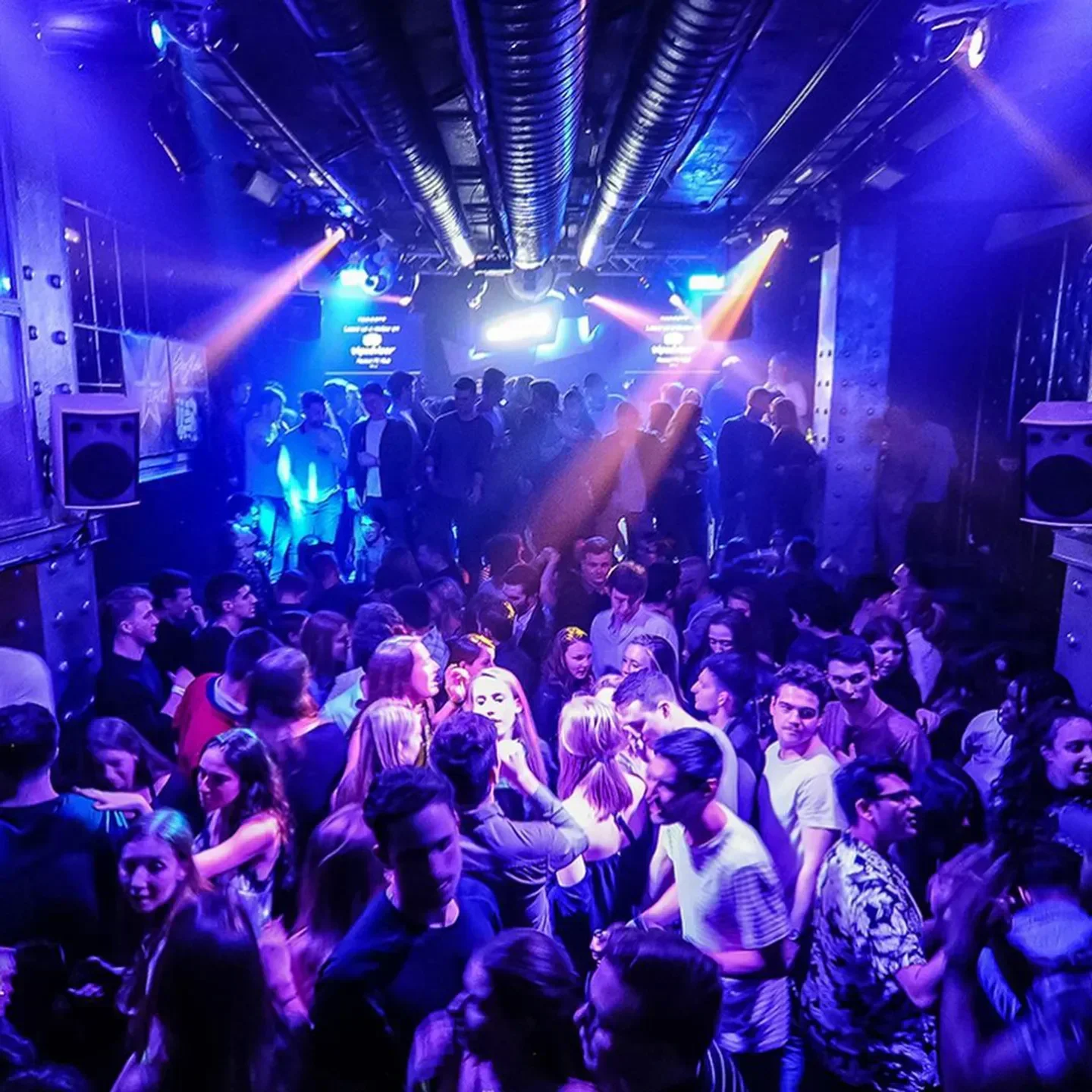 Energetic crowd partying at Radost FX nightclub in Prague, illuminated by vibrant lights.
