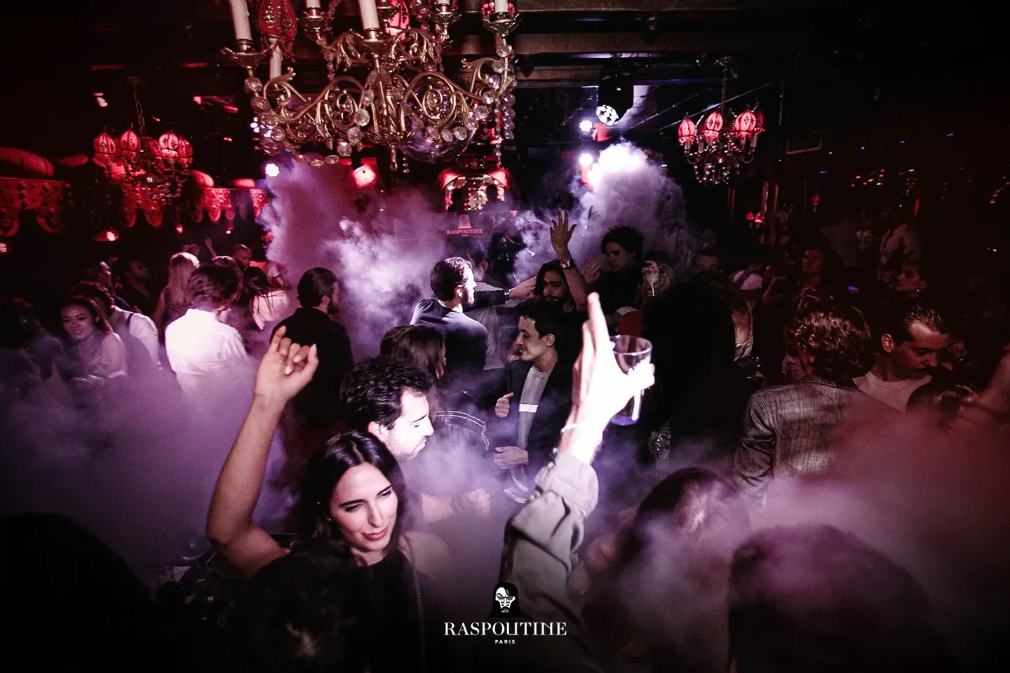Energetic nightlife scene at Raspoutine Paris, with people dancing and atmospheric fog.