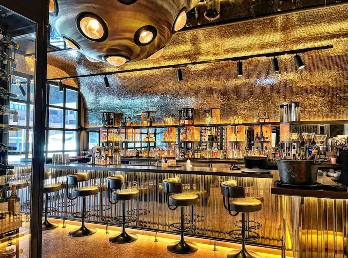 Stylish bar at RavioXO in Madrid, featuring unique lighting and a well-stocked liquor display