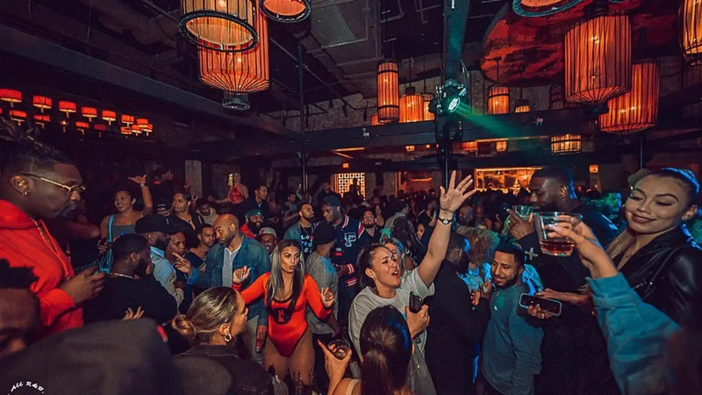 Energetic crowd partying at Red Lantern nightclub in Boston with drinks and lights.