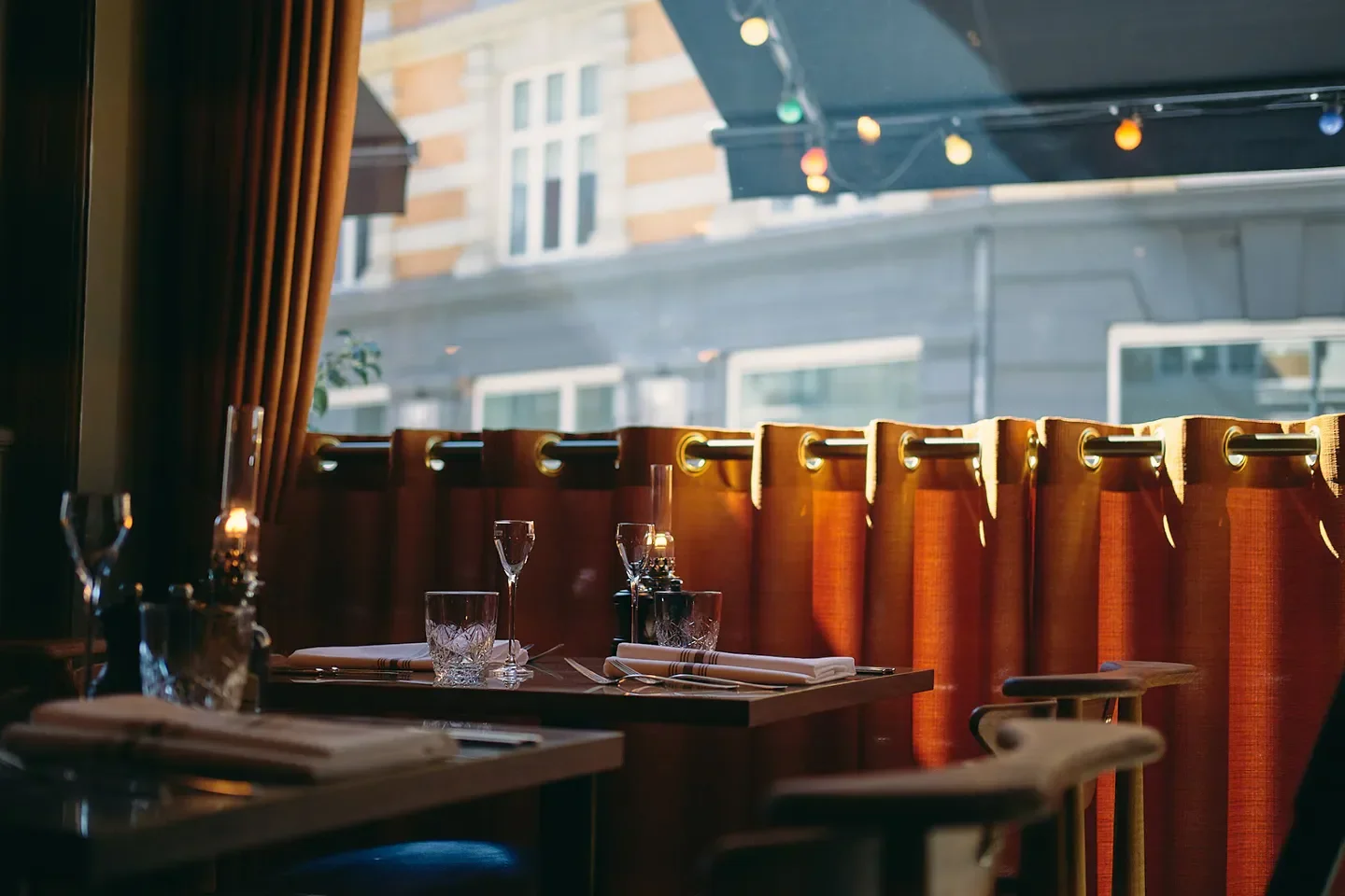 Cozy interior of Restaurant Palægade in Copenhagen, tables set with lit candles and curtains.