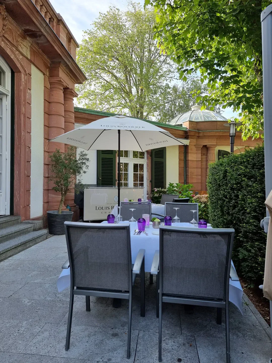 Outdoor dining at Restaurant Villa Merton in Frankfurt, elegant setting with umbrella and tables.