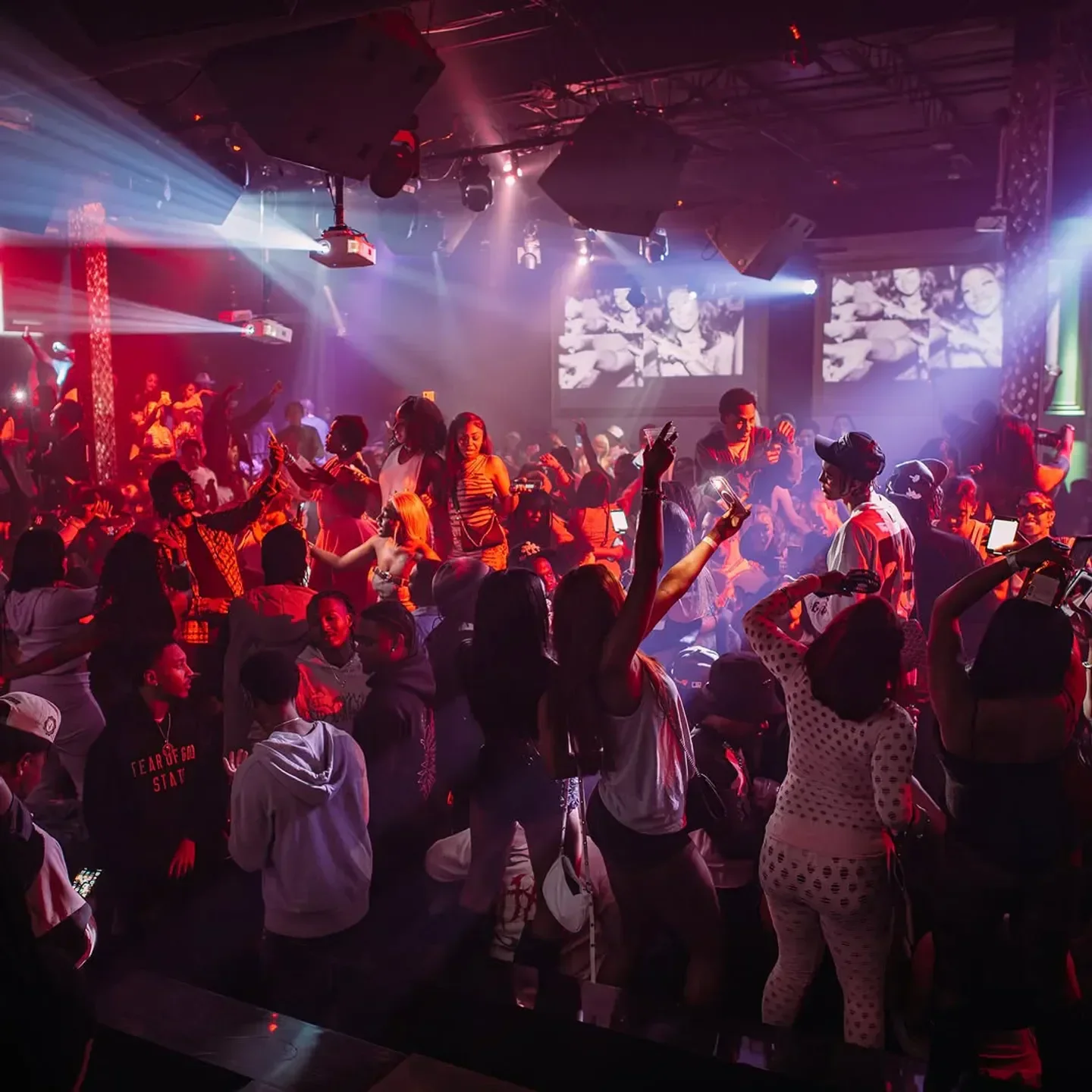 Revel Atlanta nightclub interior, people dancing under colorful stage lights and projections.