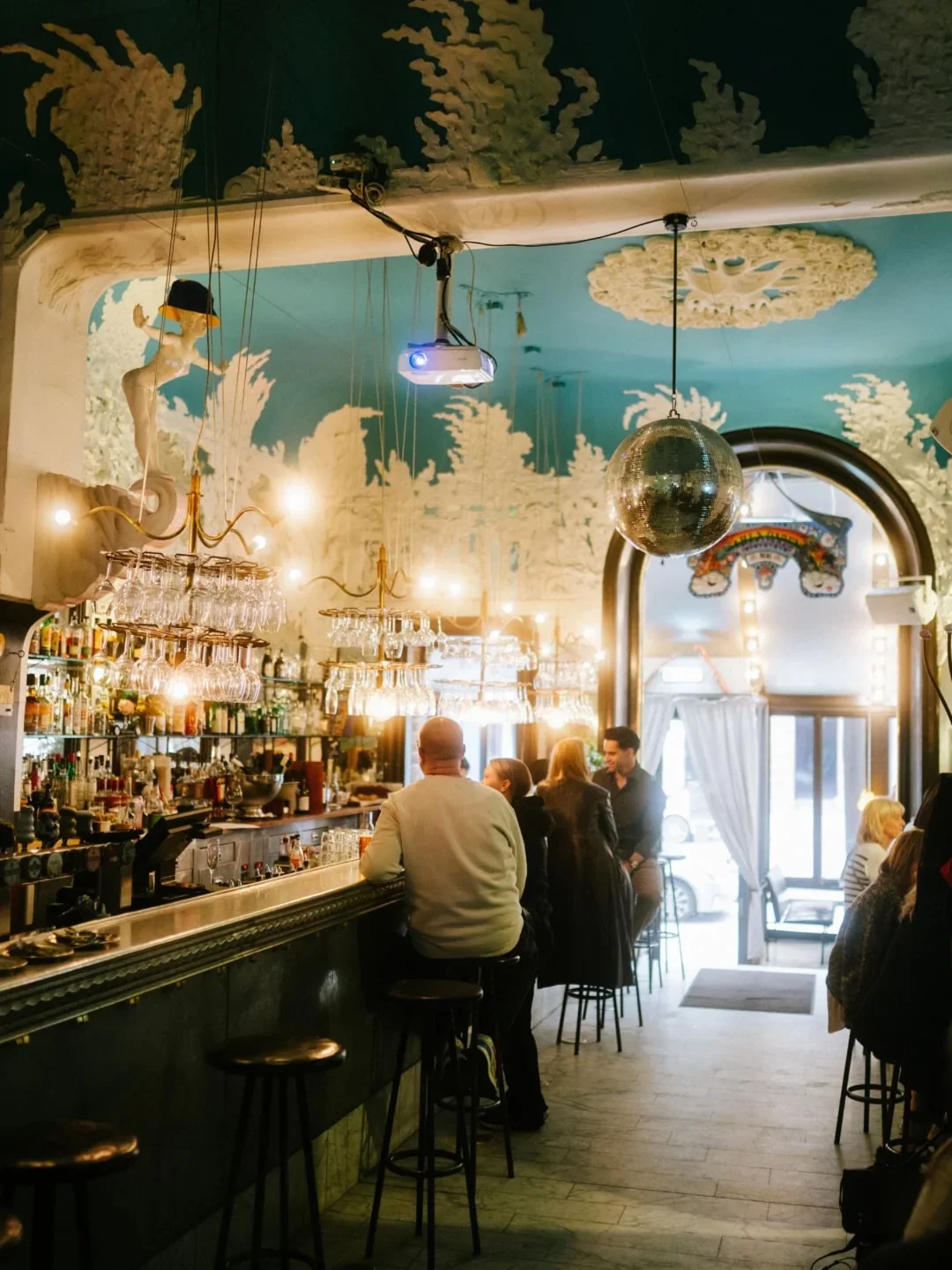 Riche restaurant interior featuring a lively bar scene with people enjoying drinks and unique ceiling decor.