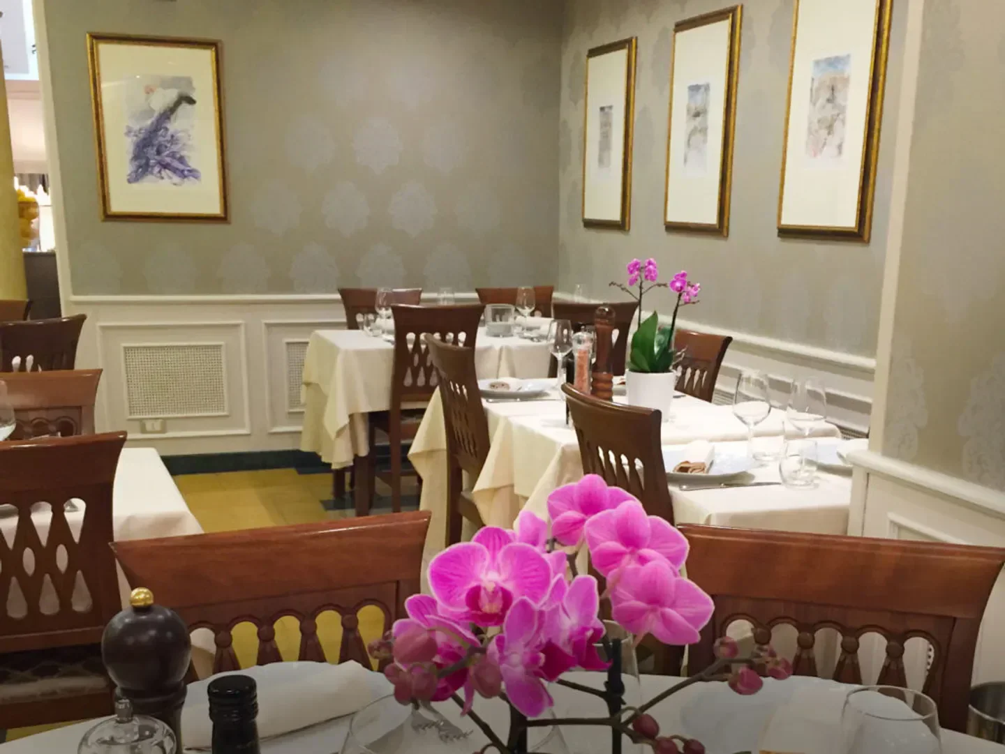 Elegant interior of Rinaldi al Quirinale restaurant in Rome, featuring orchids and framed art