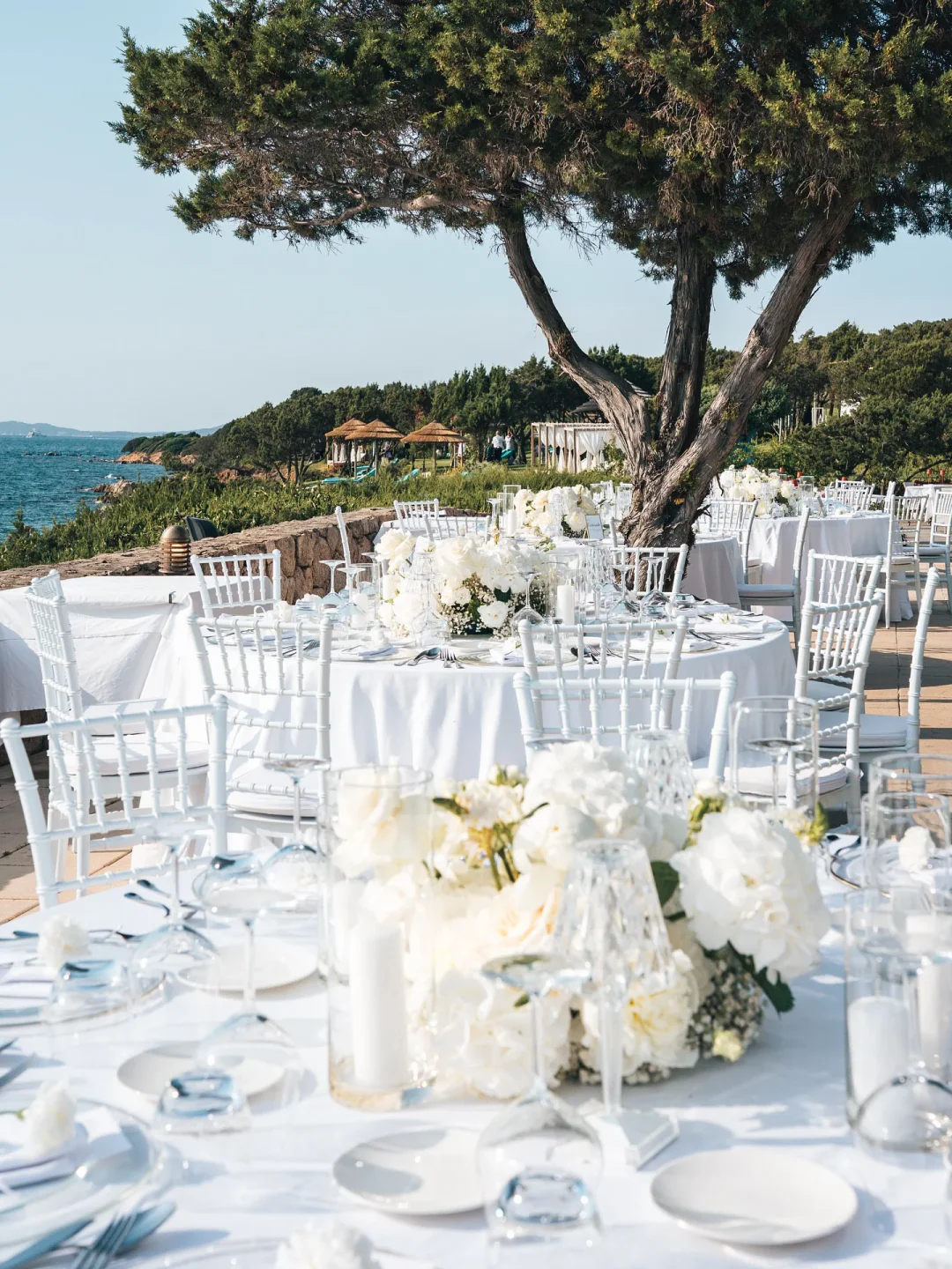 Elegant outdoor wedding setup at Rocca Beach Club Porto Cervo with white floral arrangements and sea views.