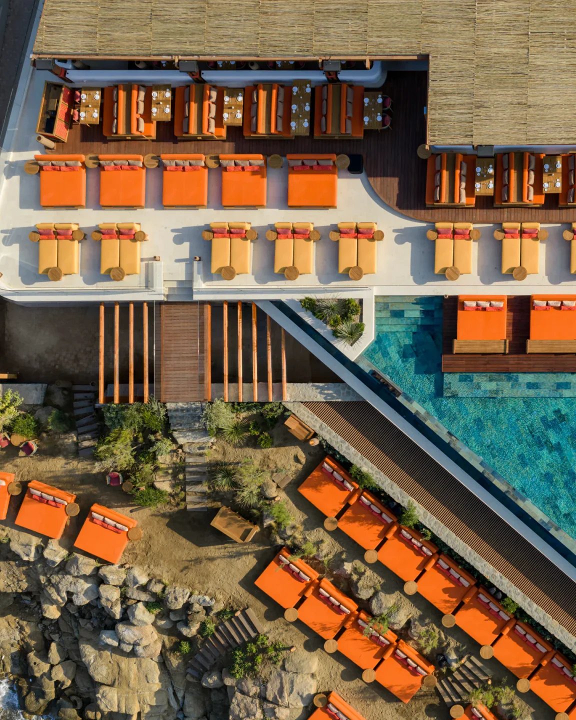 ROKA Mykonos beach club exterior with lounge chairs and pool overlooking the Aegean Sea.