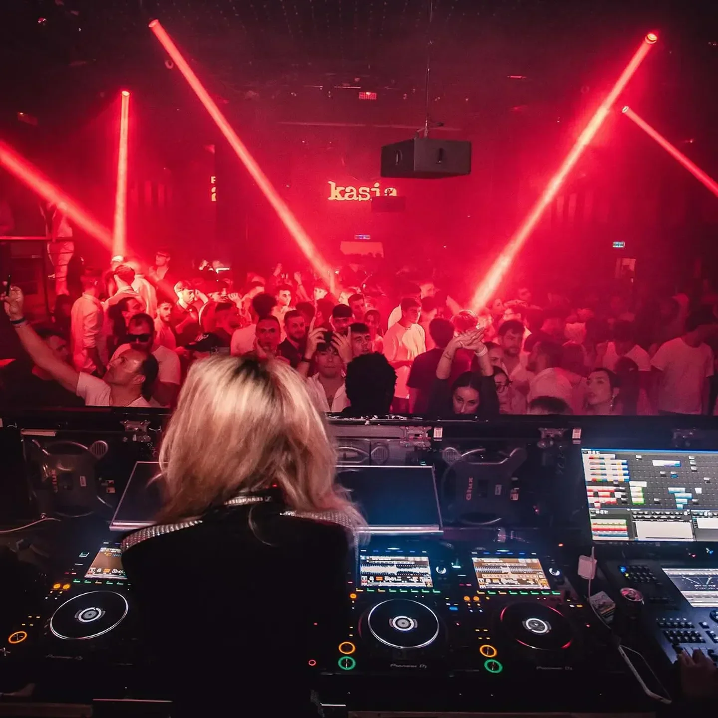 DJ at Room 26 nightclub in Rome, Italy, with energetic crowd and red lights.