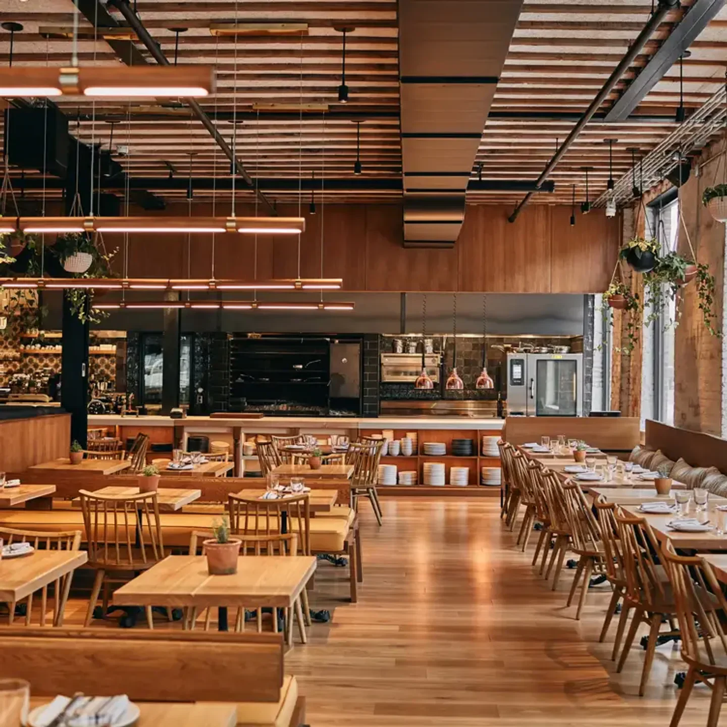 Interior of Rose Mary restaurant in Chicago with wooden tables and hanging plants