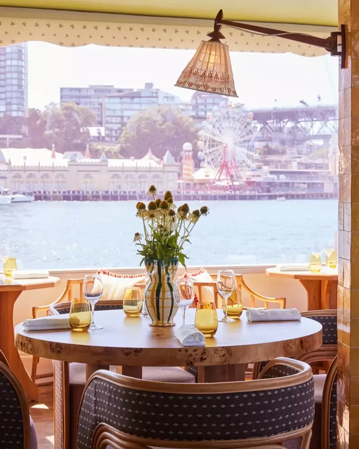 Dining table at Sails on Lavender Bay, Sydney, with harbour views and floral arrangement.