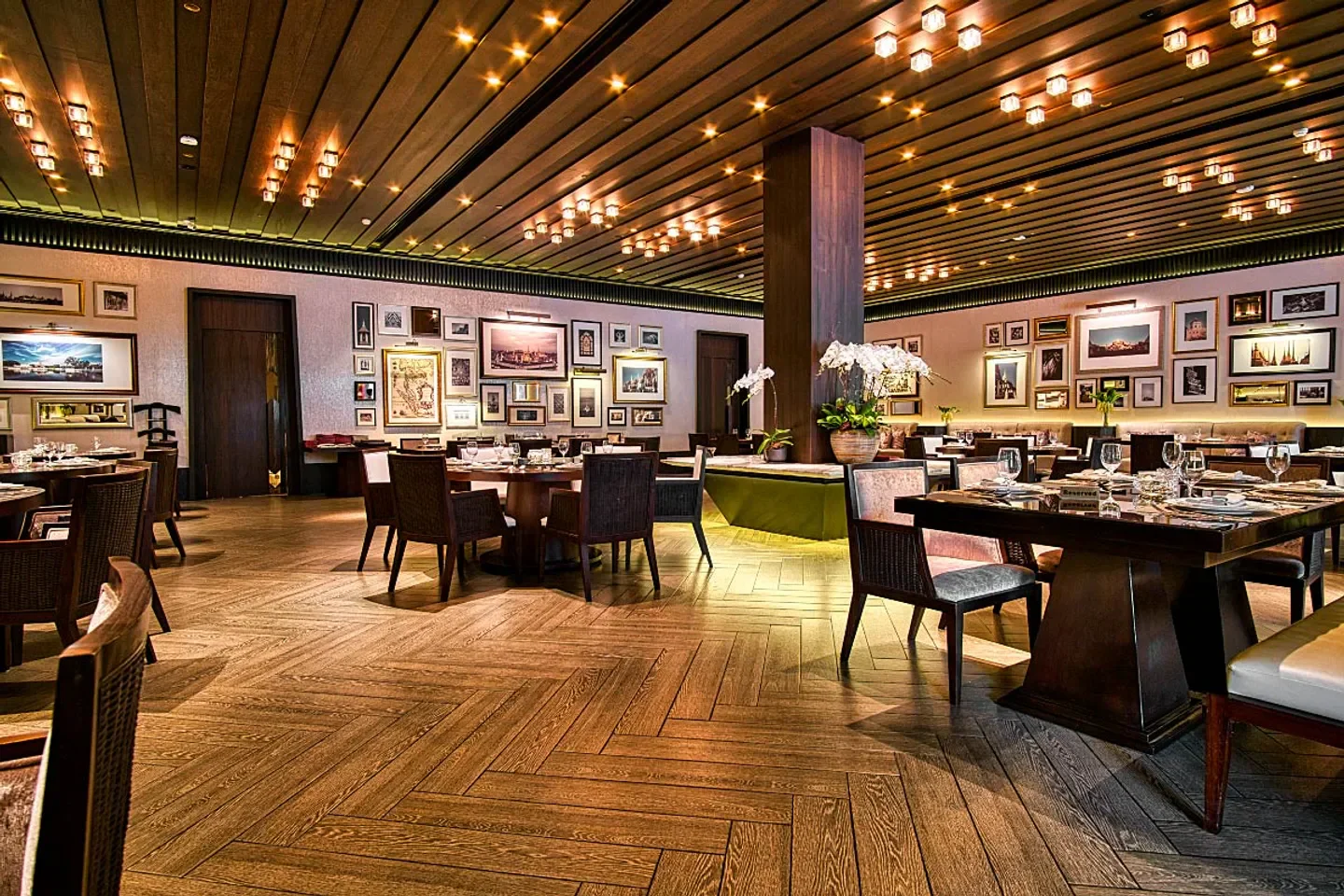 Elegant interior of Saneh Jaan restaurant in Bangkok, featuring wooden floors and artistic decor.