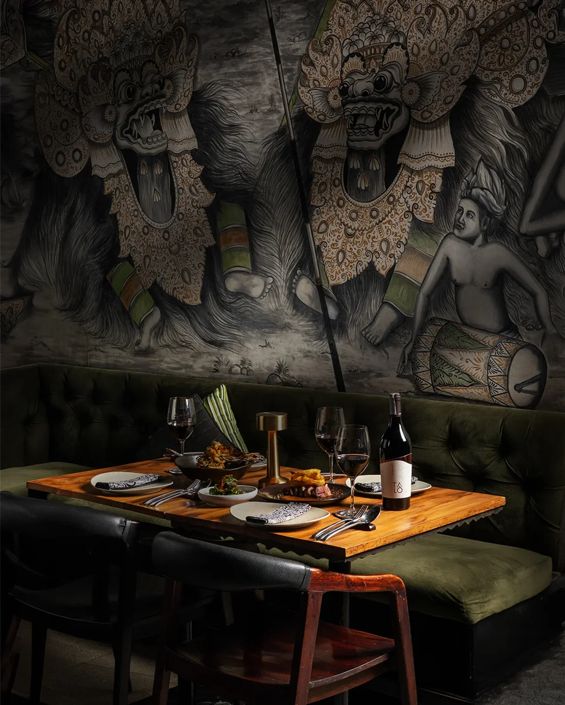 Sangsaka restaurant interior featuring a table set for dinner with traditional Balinese mural art on the wall.