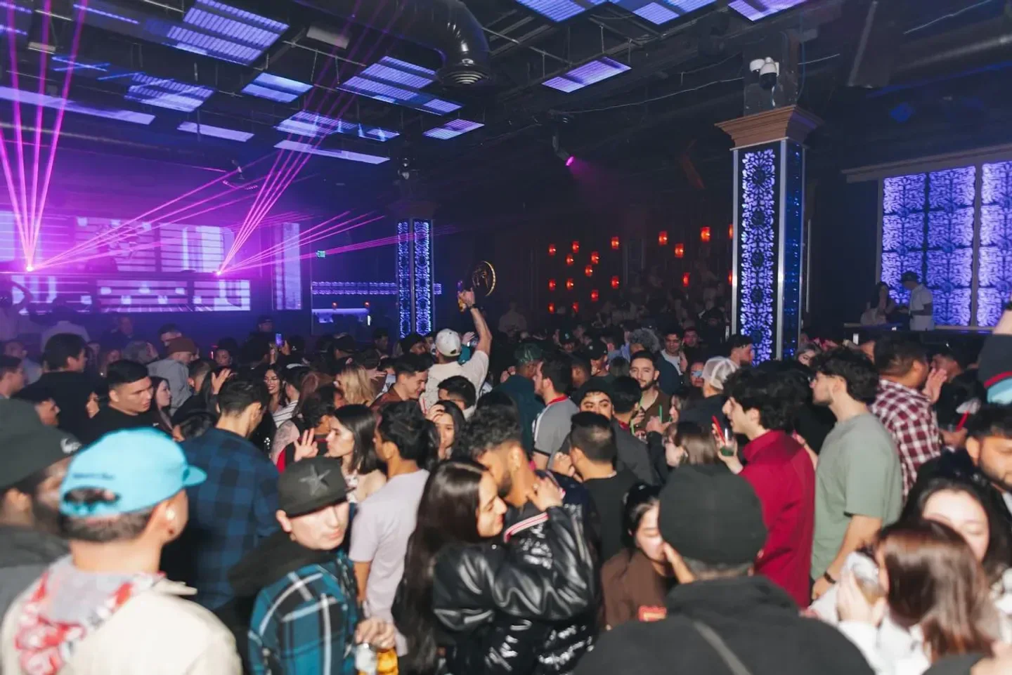 Energetic crowd inside Sarajevo Nightclub in Seattle, dancing under bright lights.