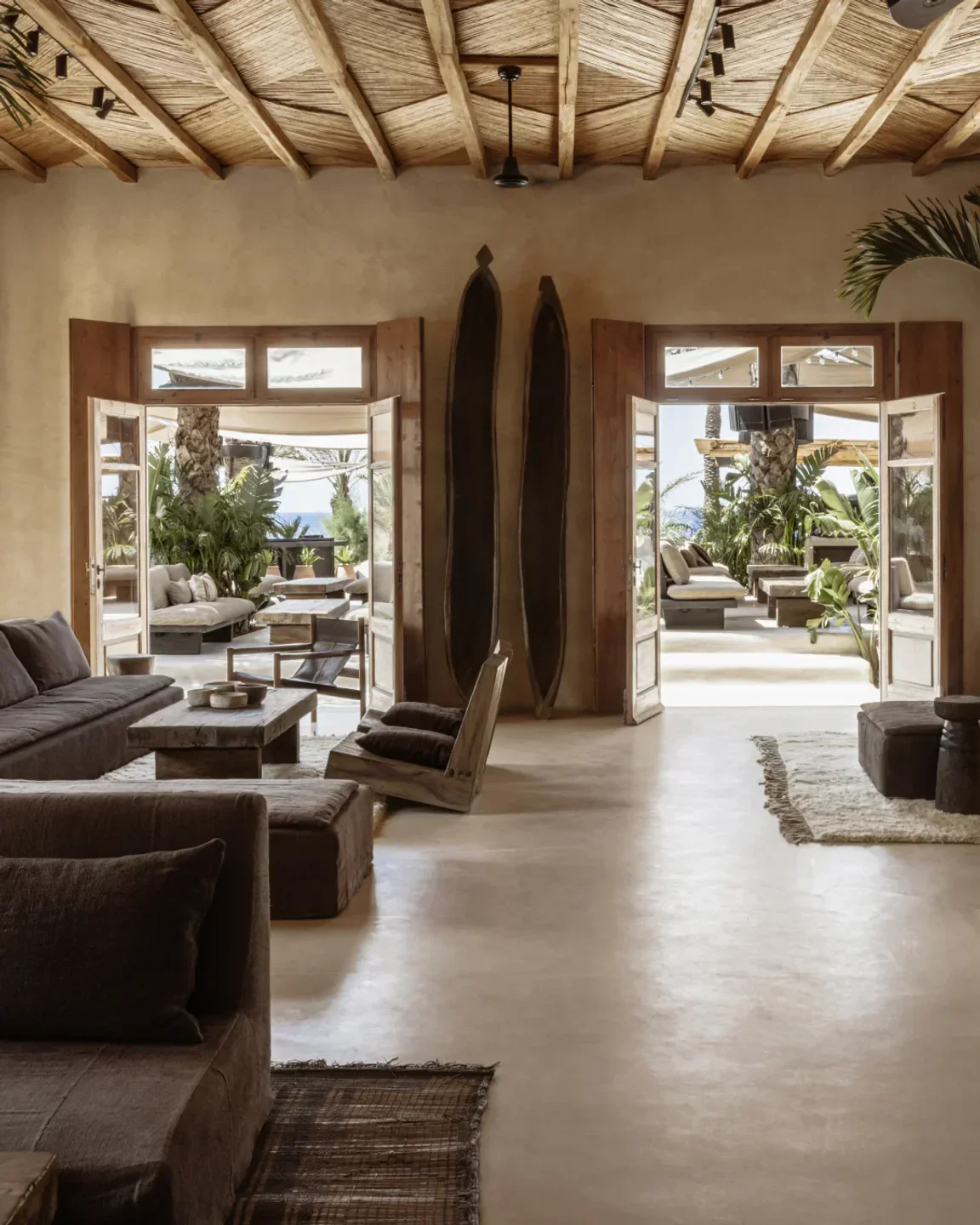 The serene interior of Scorpios beach club in Mykonos, featuring rustic wooden decor and lush greenery.
