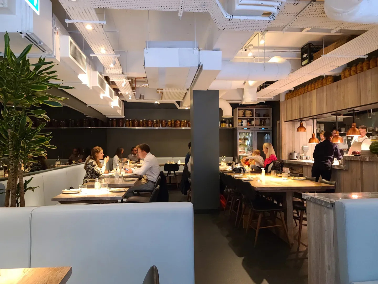 Interior of Scully St James's restaurant in London, with diners and open kitchen.