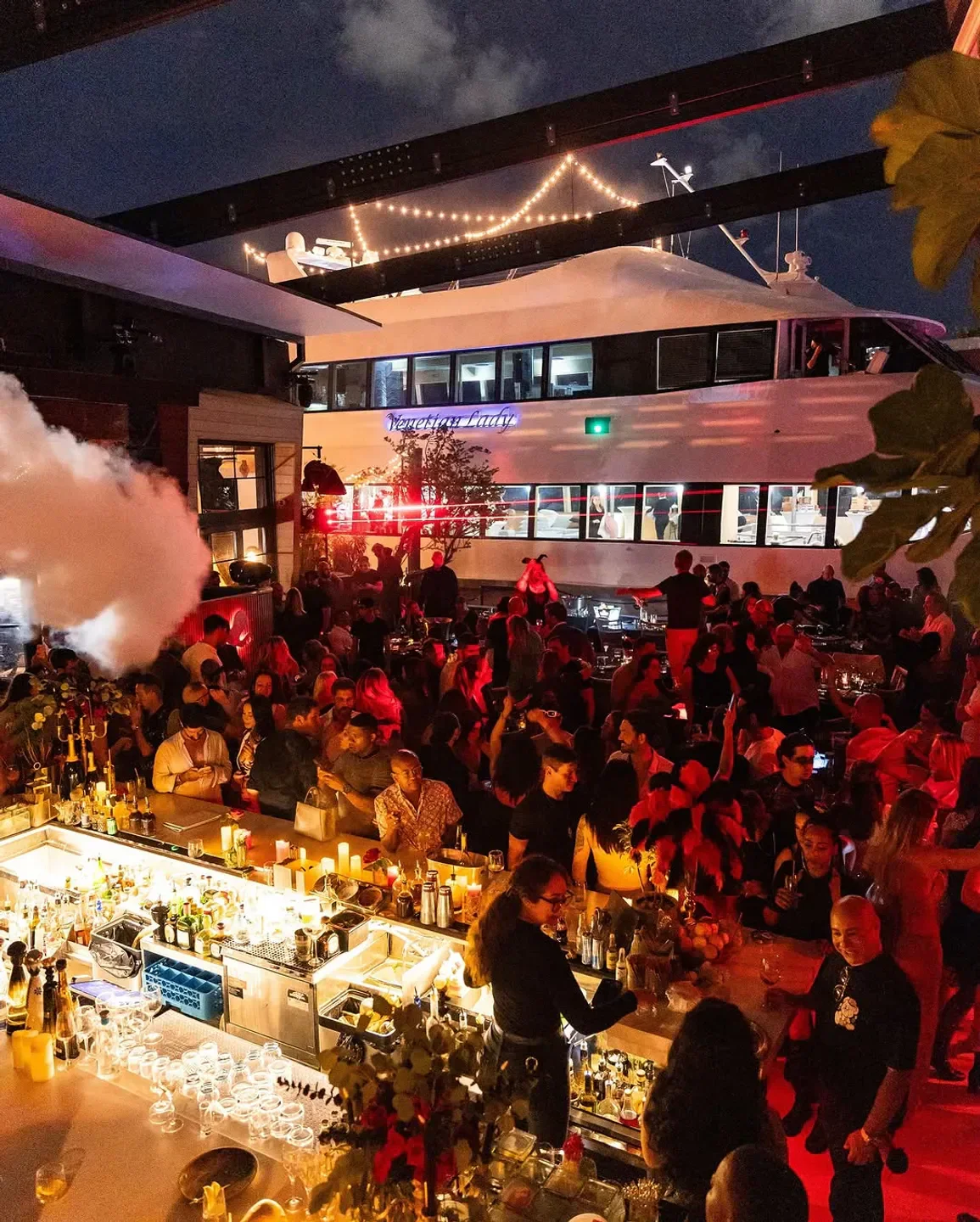 Busy bar scene at Seaspice Miami restaurant with a large boat in the background.