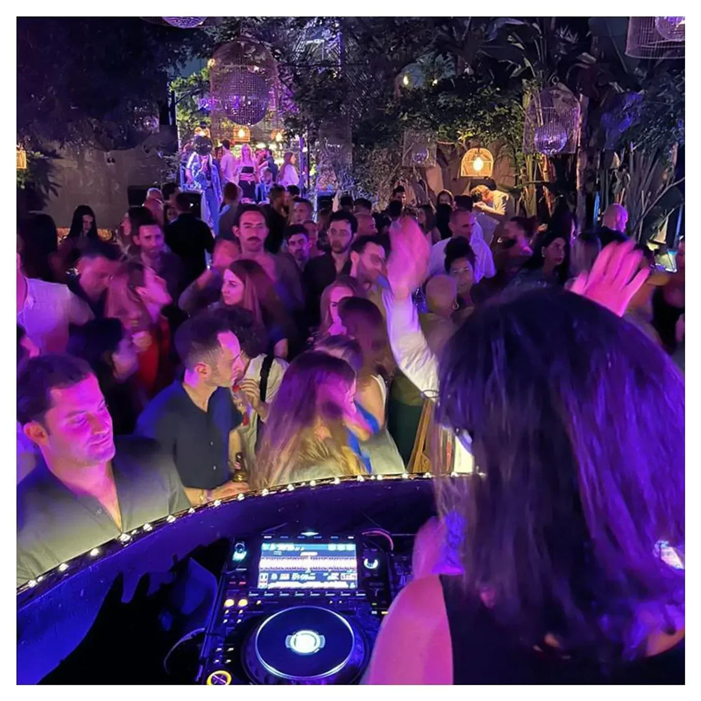 Nightclub scene at Secret Garden in Tel Aviv with DJ and dancing crowd.
