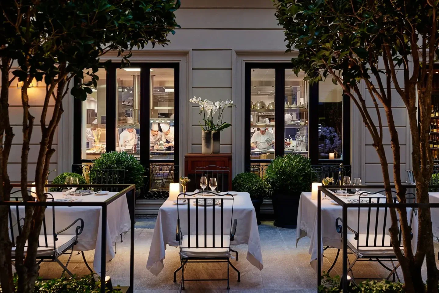 Outdoor dining at Seta in Milan, with chefs in the background preparing food.