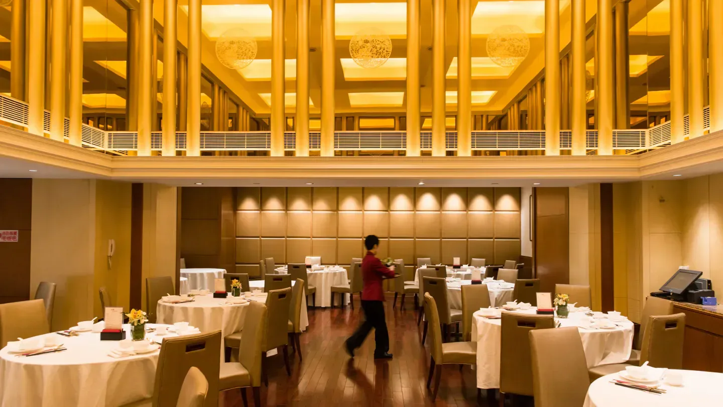 Elegant interior of Seventh Son (Wan Chai), Hong Kong restaurant with tables and staff.