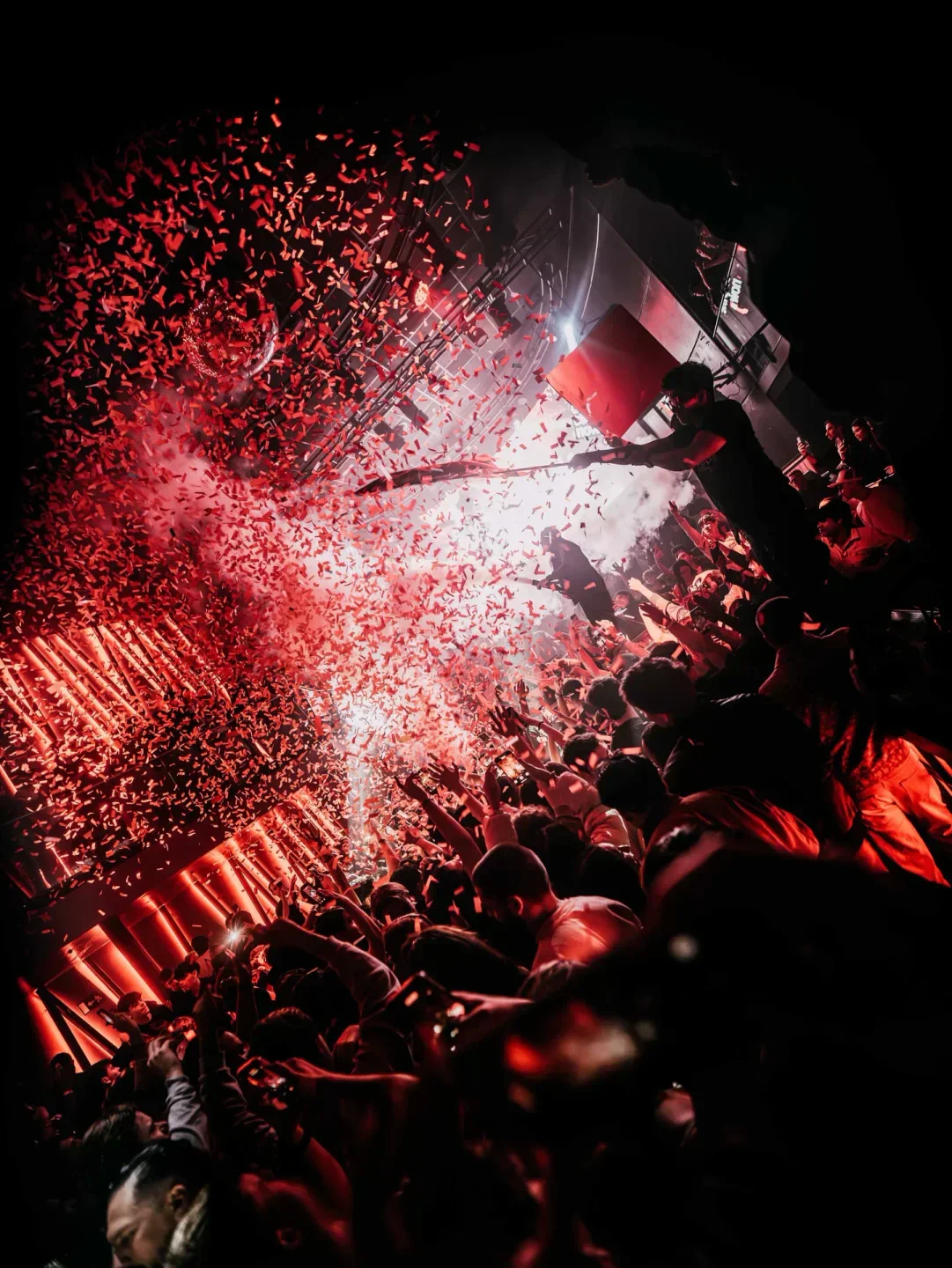 Energetic crowd celebrating with confetti at Shoko Madrid nightclub, red lights and smoke.