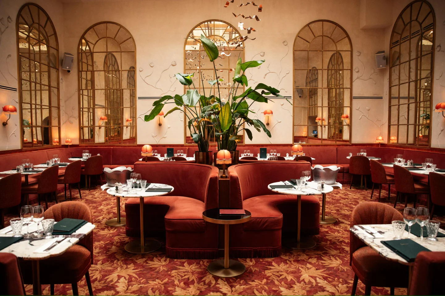 Luxurious velvet seating and ornate mirrors create an elegant dining atmosphere at Siena restaurant in Paris.