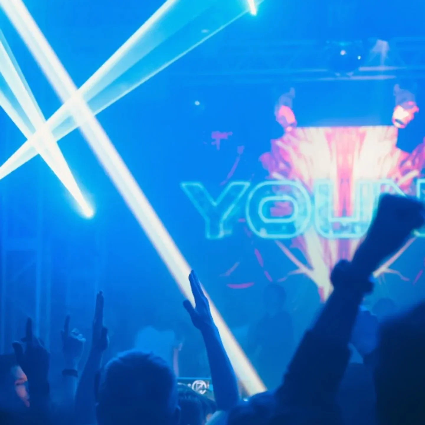 Hands raised at SILO nightclub in the city with vibrant blue laser lights and DJ stage.