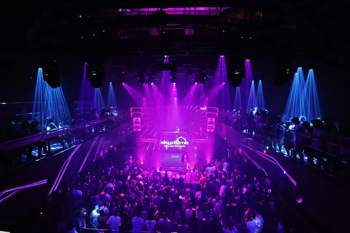 Energetic dance floor at Sky Garden nightclub in Bali, with vibrant purple and blue lights.