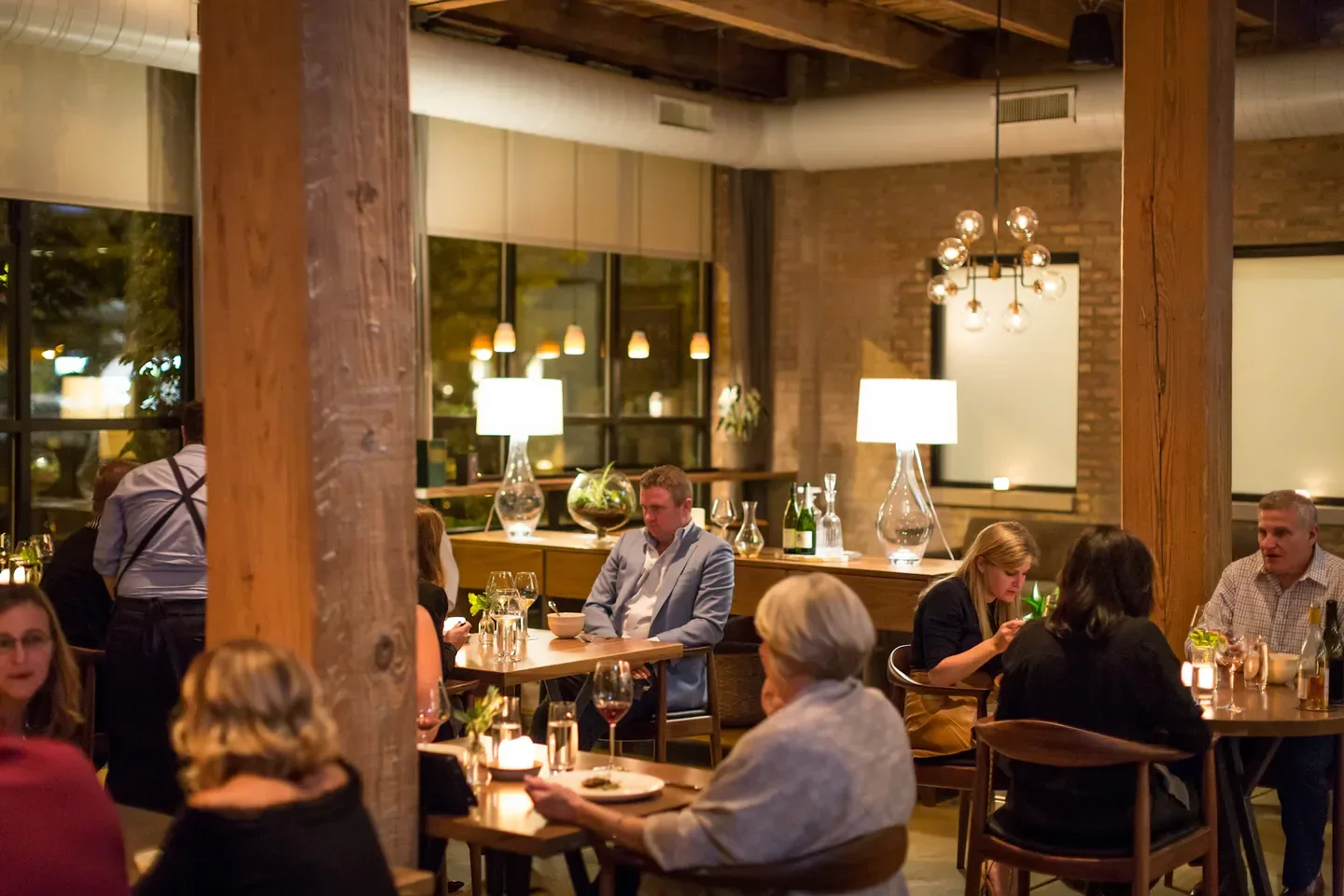 Cozy dining room at Smyth restaurant in Chicago, with diners and warm lighting.